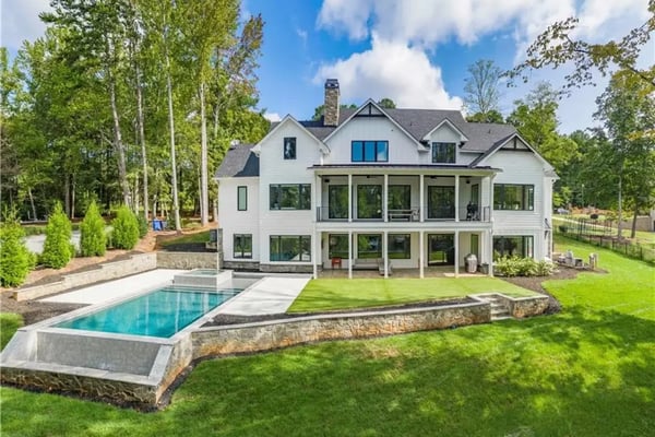 Modern white farmhouse with pool, manicured lawn, and surrounding birch trees